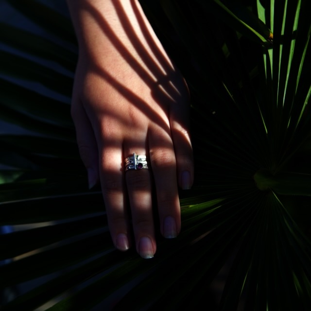 silver twine ring with a pink tourmaline gemstone and one emerald on model