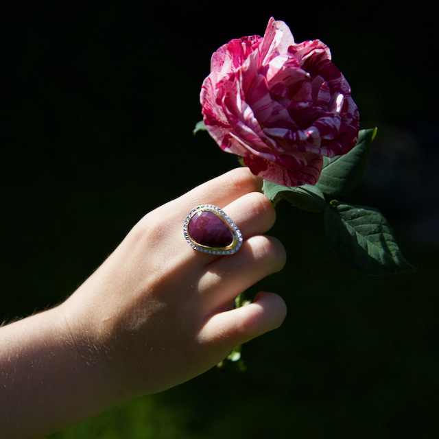 RUBY RED LEAF RING WORN – 1 RUBY RED LEAF RING SET IN 18CT GOLD, LARGE STATEMENT RING ON MODEL HOLDING A ROSE